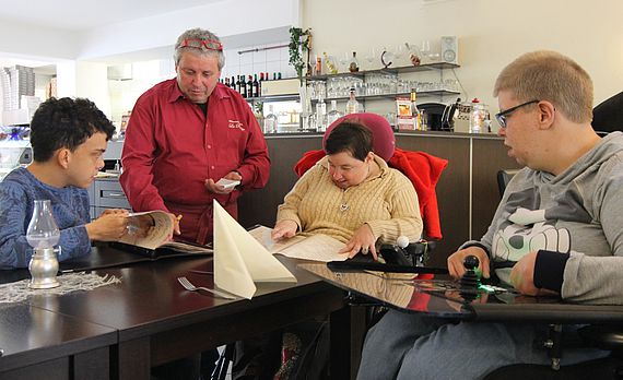In der Pizzeria hat Silvia Gau (2. von rechts) keine Probleme beim Bestellen, weil das Personal sie kennt. Für Menschen wie sie möchte das Projekt „Sokoor“ die Stadt Olsberg in Sachen Kommunikation barrierefrei machen.